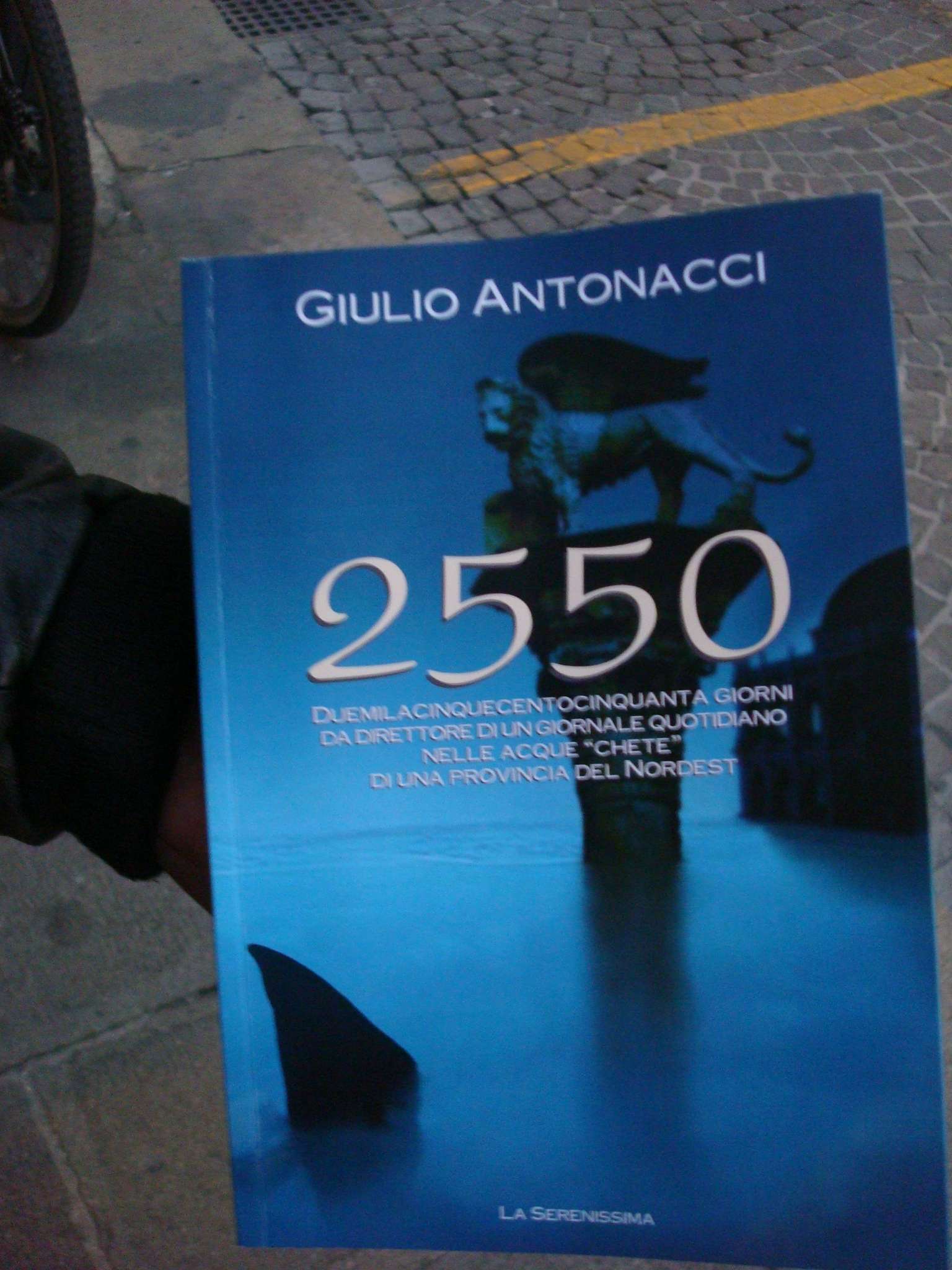 La copertina del libro di Antonacci, sullo sfondo l'acciottolato del plateatico del Bar Commercio