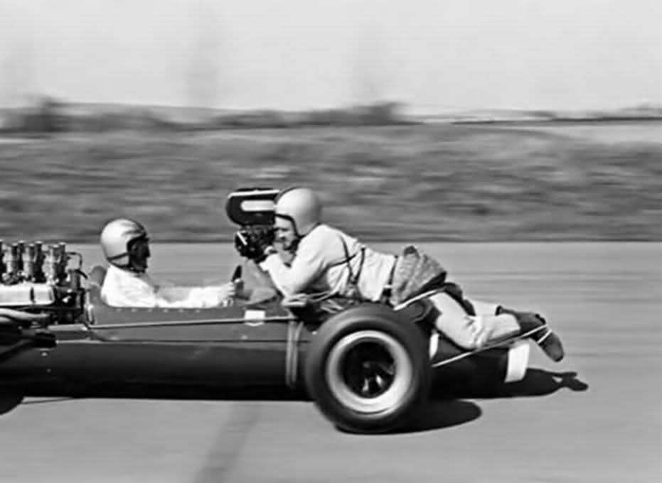 Cameraman onboard filming a race car sitted at the nose of the car